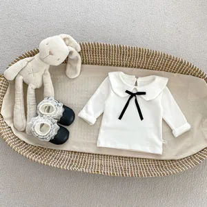 Detail der weißen Baby-Baumwollbluse mit Peter-Pan-Kragen und schwarzer Samtschleife