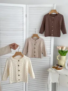 Detail view of children's cable knit cardigans with vintage buttons in neutral tones