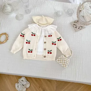 Flat lay di cardigan in maglia per neonati con ricamo ciliegia e set colletto in pizzo