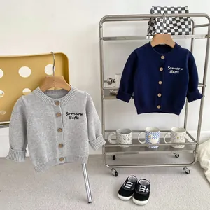 Dettaglio del ricamo e dei bottoni in legno sui cardigan in maglia per bambini