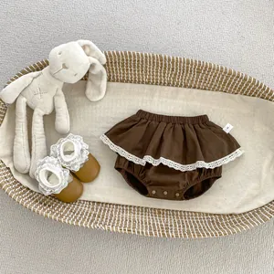 Detail der braunen Baby-Pumphose mit Rüschen, Spitzenbesatz und Druckknöpfen im Korb