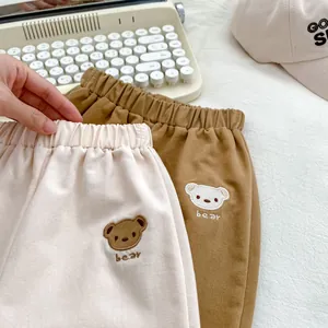 Dettaglio del ricamo a forma di orsetto e vita elastica sui pantaloni in cotone per bimbi