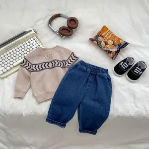 Flat lay of boys beige knit sweater with geometric pattern and dark blue casual pants