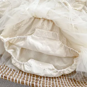 Detail of baby romper bottom with floral lace, tulle mesh, and three snap buttons