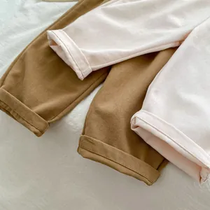 Dettaglio dei risvolti dei pantaloni per bambini in cotone caramello e rosa con cuciture fini