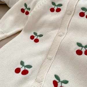 Dettaglio del cardigan in maglia per neonato con ricami a ciliegia e bottoni