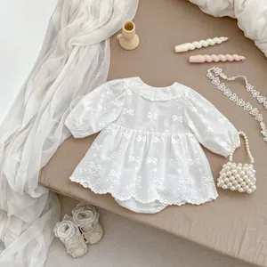 Body neonata bianco con ricamo a fiocco e accessori abbinati presentati in una posa piatta