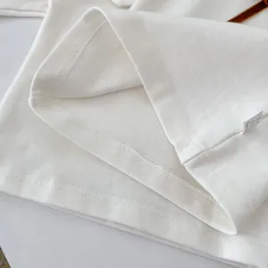 Nahaufnahme des weißen Baumwolltops mit feinen Nähten und Details zum Pflegeetikett