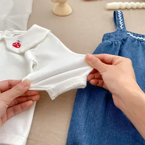 Detail of baby outfit showing embroidery on Peter Pan collar and stretch cotton fabric