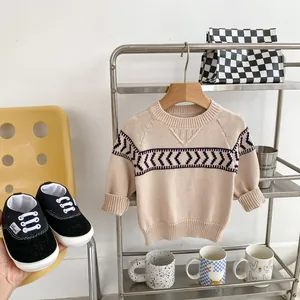 Beige boys knit sweater with navy patterns and black baby shoes in Nordic style setting