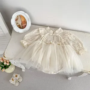 Detail of baby girl's cream romper dress with lace ruffles and matching soft shoes