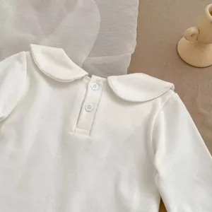 Close-up of white baby doll shirt with Peter Pan collar and back button details