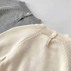 Detail of baby knitted jumpsuits showing textured stitching and back button closure