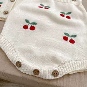 Dettaglio body neonato in maglia con ricamo a ciliegia e bottoni in legno naturali