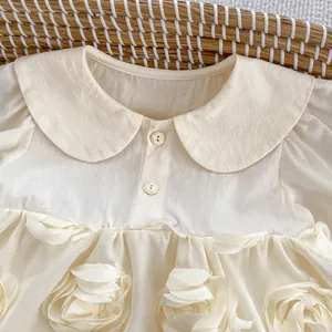 Detail of baby cream dress with Peter Pan collar and decorative 3D floral accents