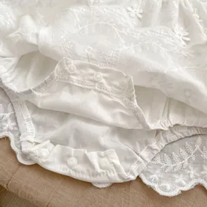 Detailed macro view of baby bodysuit snap fasteners and fine floral embroidery edges