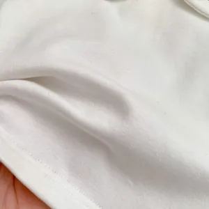 Close-up of white knitted cotton fabric hem with neat single needle stitching detail