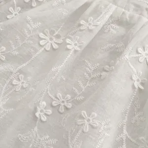 Detailed view of white cotton fabric with exquisite floral embroidery for baby dress