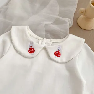 Detail of white Peter Pan collar with delicate mushroom and rabbit embroidery on baby shirt