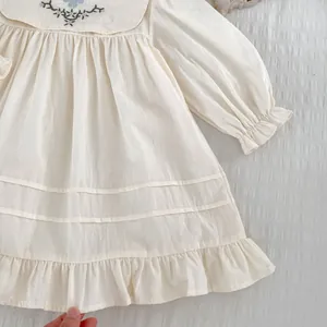 Detailaufnahme der Blumenstickerei auf cremefarbenem Kleid mit gerafften Ärmelbündchen