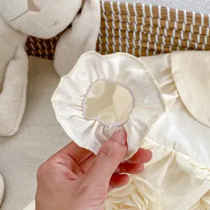 Detail shot of baby romper elastic ruffle cuffs on soft cream cotton fabric
