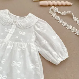 Dettaglio vestito neonata in cotone bianco con colletto Peter Pan e ricamo