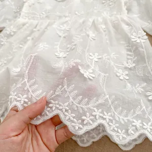 Elegant white lace baby bodysuit featuring floral embroidery and scalloped edges for girls