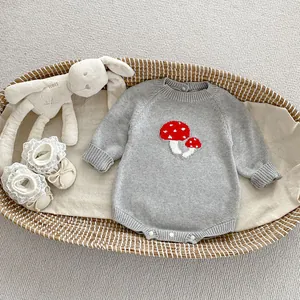 Close-up of grey knit baby romper with red mushroom embroidery in a woven basket
