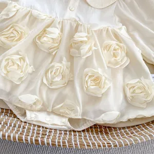 Close-up of cream baby romper featuring 3D chiffon rose detail and snap buttons