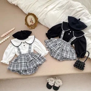 Dettaglio flat lay del set a quadretti per neonata con colletto a balze e accessori