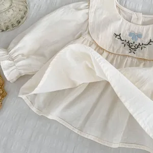 Detailansicht der Mädchenbluse in Creme mit Stickereien und blauer Schleife