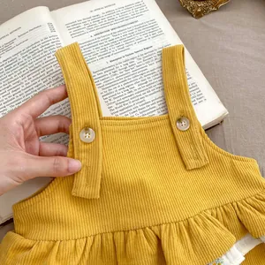 Detail of ginger yellow corduroy baby girl jumper with wooden buttons and ruffle hem