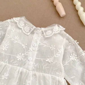 Detail of white baby bodysuit featuring floral embroidery and lace collar accents
