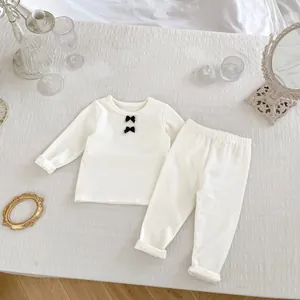 Detailansicht der cremefarbenen Baby-Homewear mit Rippstruktur und schwarzen Schleifen