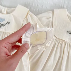 Details elastischer Rüschenmanschetten und Blumenstickerei am beigen Babykleid