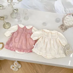 Détail de robe bébé avec appliqués de roses 3D et volants délicats en dentelle