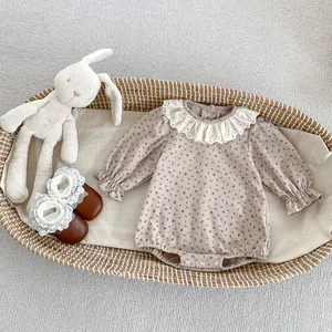 Détail d'un body bébé floral avec col en dentelle et volants dans un berceau
