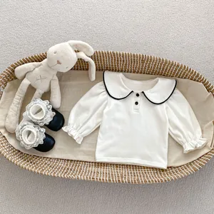 Dettaglio maglia crema neonata con colletto a bambola e polsini a volant elastici