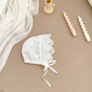 Detailed top view of a white vintage lace baby bonnet with floral embroidery and ties