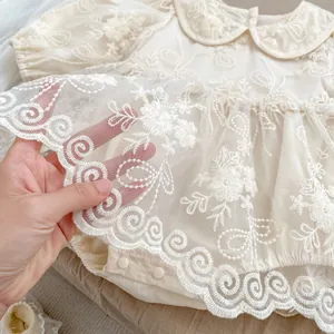 Dettaglio body neonata con ricami in pizzo floreale e colletto stile Peter Pan