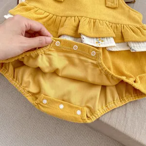 Detail of baby floral romper with corduroy fabric and metal snap buttons at the bottom