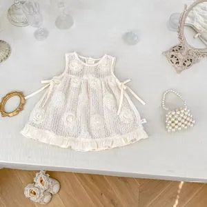 Détail de la robe en dentelle pour bébé avec fleurs 3D et nœuds en ruban doux