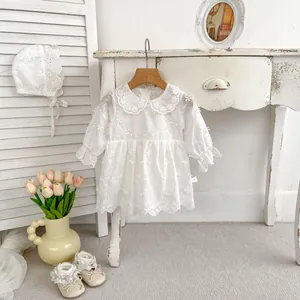 Detail of white infant lace romper dress with floral embroidery and matching accessories