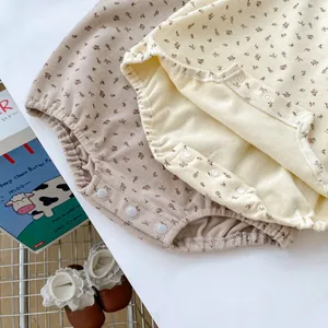 Détail d'un barboteuse pour bébé à fleurs montrant le tissu en coton et les boutons