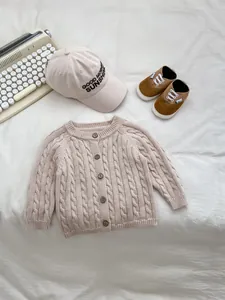 Pagliaccetto neonato beige a trecce in maglia con bottoni in legno su sfondo bianco