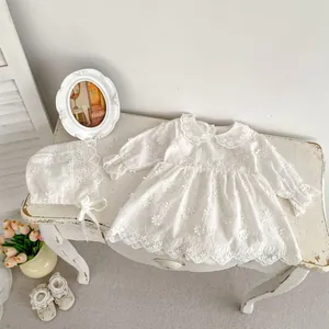 Detail of white cotton lace baby romper dress with floral embroidery and matching sun hat