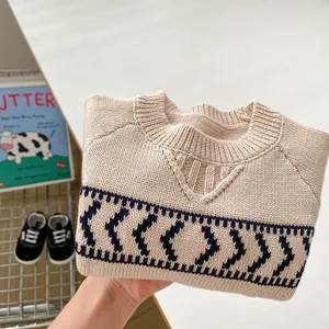 Close-up of baby beige knit sweater with navy blue geometric patterns and ribbed crewneck