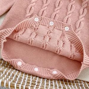 Detailaufnahme des rosa Strick-Babybodys mit Zopfmuster und Druckknöpfen im Schritt