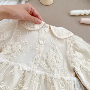 Dettaglio del vestito da neonata con ricamo floreale e colletto Peter Pan in pizzo