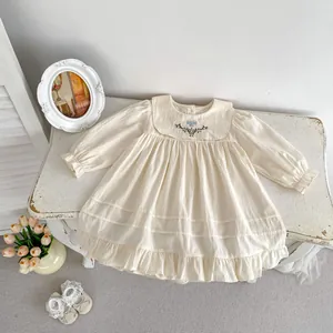 Detail des bestickten Peter-Pan-Kragens mit blauem Blumenmuster auf cremigem Kleid